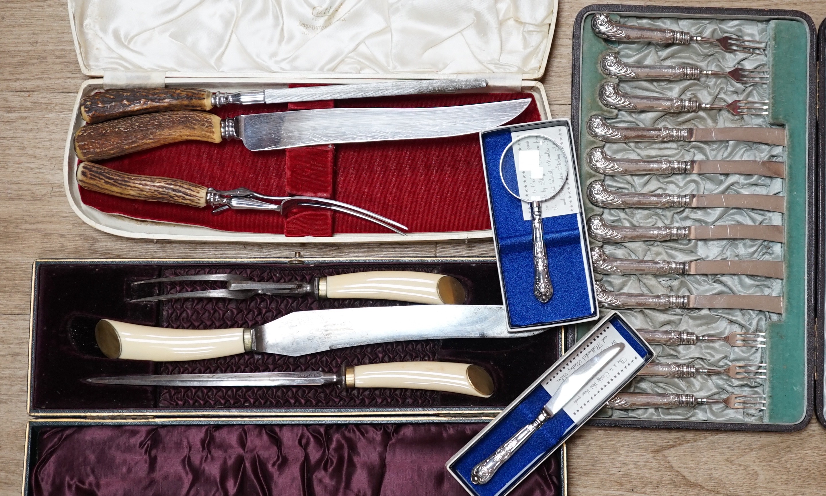 Two cased plated carving sets, a cased set of silver handled cake knives, a modern silver handled magnifying glass and cake slice.